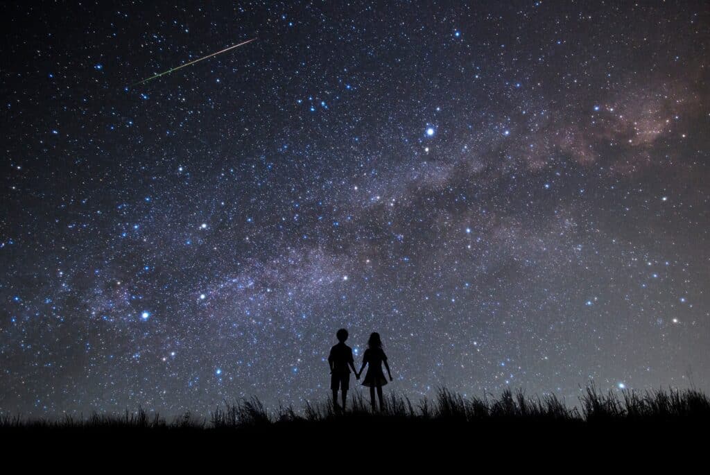 A silhouette of a couple looking up at the Milky Way.