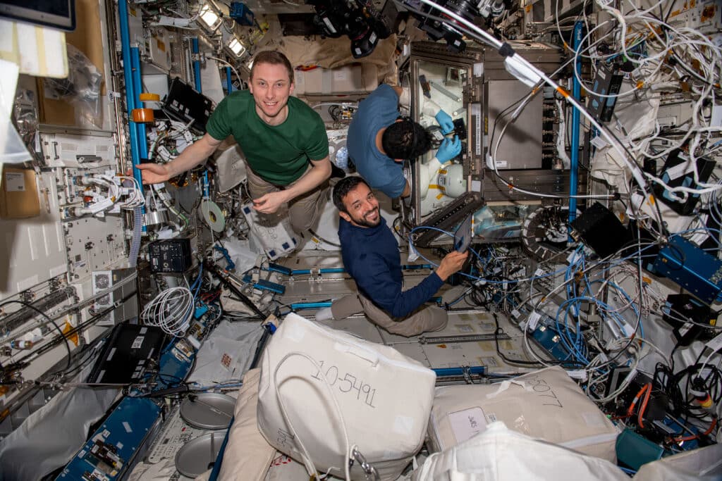 Three Expedition 69 flight engineers are pictured working on a variety of tasks inside the International Space Station's Kibo laboratory module