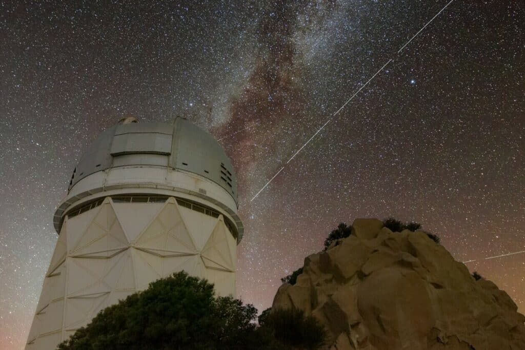 Trails in the night sky left by BlueWalker 3 are juxtaposed against the Nicholas U. Mayall 4-meter Telescope at Kitt Peak National Observatory in Arizona.