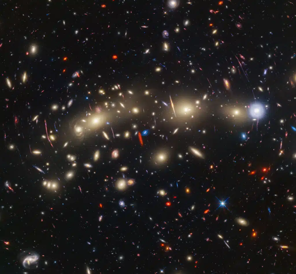 This panchromatic view of galaxy cluster MACS0416 was created by combining infrared observations from NASA’s James Webb Space Telescope with visible-light data from NASA’s Hubble Space Telescope.