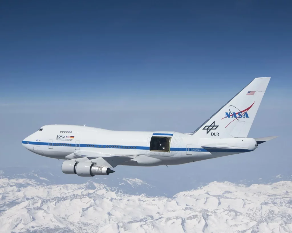 SOFIA soars over the snow-covered Sierra Nevada mountains with its telescope door open during a test flight. SOFIA is a modified Boeing 747SP aircraft.