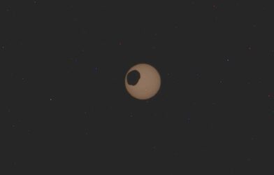 The potato-shaped Mars moon of Phobos transits from top to bottom left across the Sun, February 8, 2024.