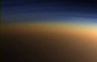 In the upper layer of Titan's atmosphere, visible here in blue light, methane molecules are being dissociated by sunlight and recombining into ethane and acetylene molecules
