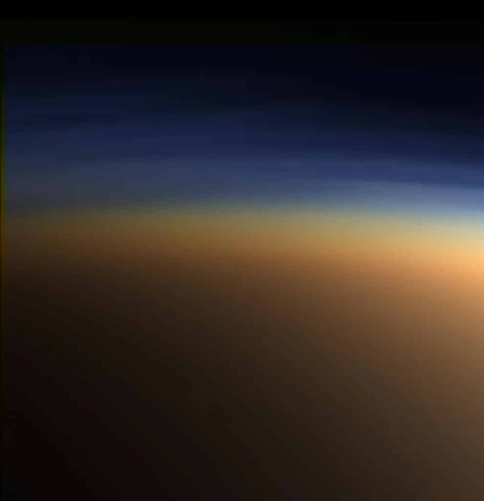 In the upper layer of Titan's atmosphere, visible here in blue light, methane molecules are being dissociated by sunlight and recombining into ethane and acetylene molecules
